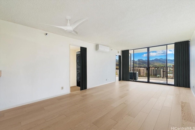 990 Ala Nanala St Unit 27D, Honolulu, HI 96818 - unfurnished room featuring expansive windows, light wood-style floors, a textured ceiling, a wall unit AC, and a ceiling fan