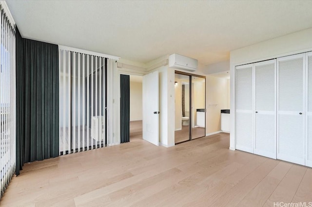 990 Ala Nanala St Unit 27D, Honolulu, HI 96818 - unfurnished bedroom with a wall unit AC, wood finished floors, and multiple closets