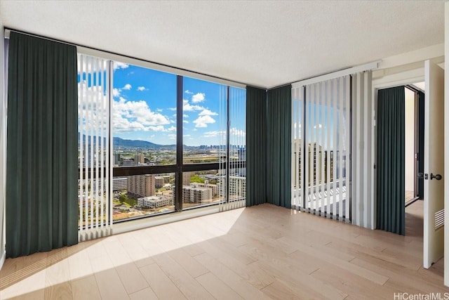 990 Ala Nanala St Unit 27D, Honolulu, HI 96818 - empty room with floor to ceiling windows, wood finished floors, and a textured ceiling