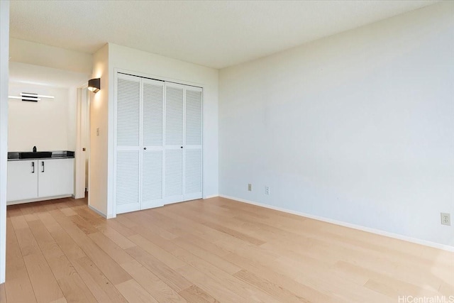 990 Ala Nanala St Unit 27D, Honolulu, HI 96818 - unfurnished bedroom with light wood finished floors, a closet, and baseboards