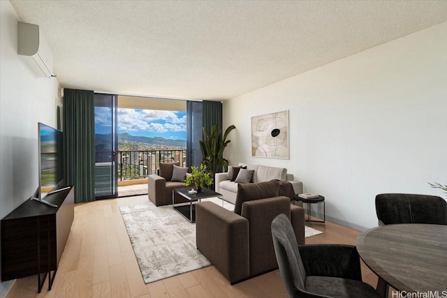 990 Ala Nanala St Unit 27D, Honolulu, HI 96818 - living area with expansive windows, light wood-style floors, a wall unit AC, and a textured ceiling