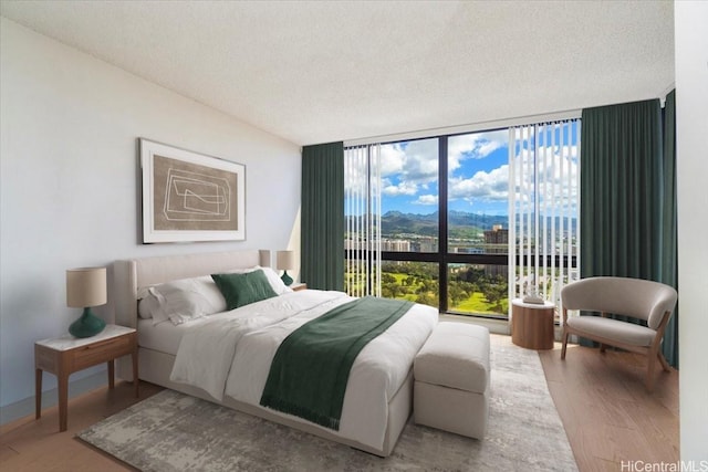 990 Ala Nanala St Unit 27D, Honolulu, HI 96818 - bedroom with expansive windows, wood finished floors, a textured ceiling, and a mountain view