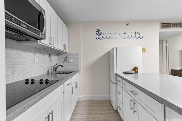 1088 Bishop St Unit 1008, Honolulu, HI 96813 - kitchen with stainless steel microwave, a sink, backsplash, baseboards, and white cabinetry
