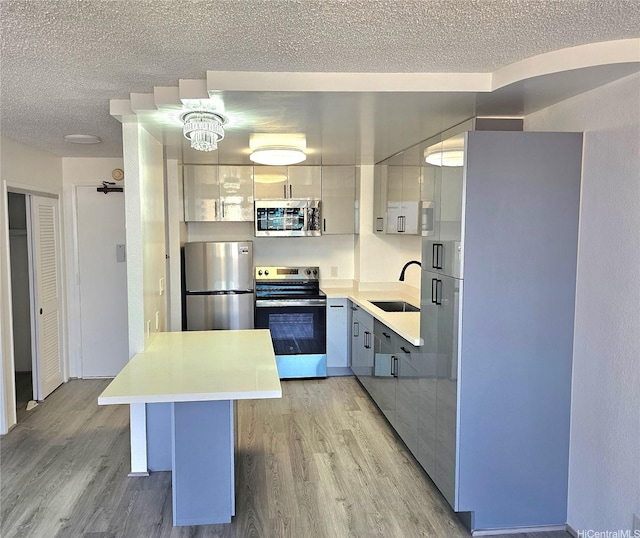 1255 Nuuanu Ave Unit E2811, Honolulu, HI 96817 - kitchen with stainless steel appliances, a sink, light wood-type flooring, a textured ceiling, and light countertops