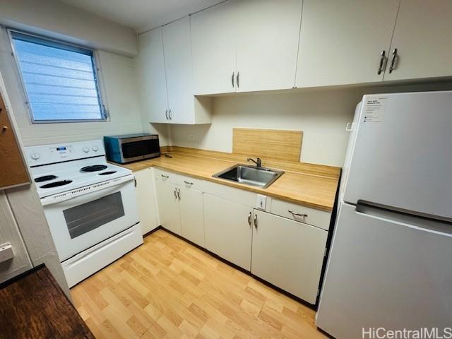 417 Nohonani St Unit 311, Honolulu, HI 96815 - kitchen with freestanding refrigerator, white electric range, stainless steel microwave, white cabinets, and light wood-style floors