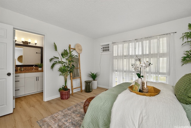 7528 Olili Pl, Honolulu, HI 96825 - bedroom with light wood-style flooring, a wall mounted air conditioner, connected bathroom, and a textured ceiling