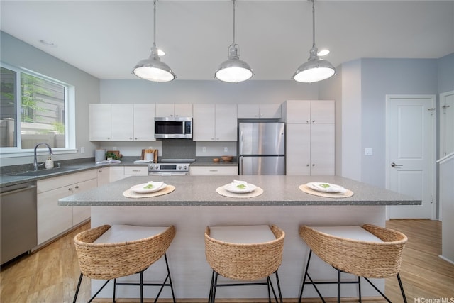 91-1160 Kamakana St Unit 608, Ewa Beach, HI 96706 - kitchen featuring appliances with stainless steel finishes, a kitchen breakfast bar, white cabinets, light wood-type flooring, and pendant lighting
