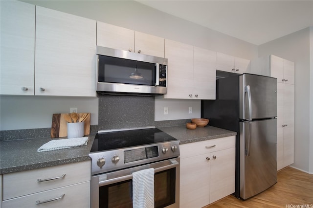 91-1160 Kamakana St Unit 608, Ewa Beach, HI 96706 - kitchen with appliances with stainless steel finishes, light wood-type flooring, dark stone counters, and backsplash