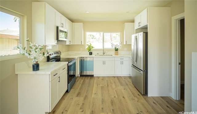 84-160 Jade St, Waianae, HI 96792 - kitchen with stainless steel appliances, a sink, light wood-type flooring, and white cabinets