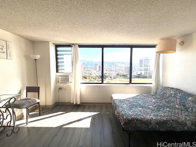 444 Niu St Unit 1312, Honolulu, HI 96815 - bedroom featuring a textured ceiling, wood finished floors, a view of city, baseboards, and cooling unit