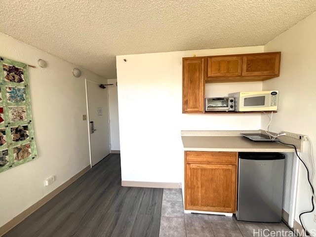 444 Niu St Unit 1312, Honolulu, HI 96815 - kitchen with refrigerator, brown cabinets, white microwave, a textured ceiling, and wood finished floors
