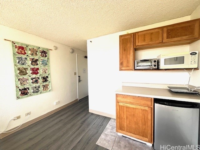 444 Niu St Unit 1312, Honolulu, HI 96815 - kitchen with white microwave, a textured ceiling, dark wood-style floors, brown cabinetry, and light countertops