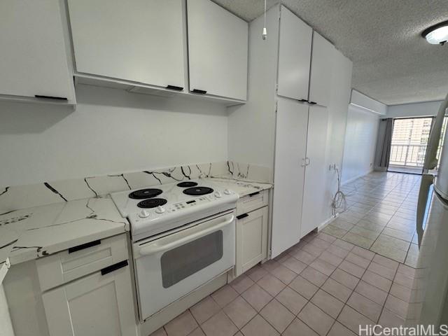 303 Liliuokalani Ave Unit 602, Honolulu, HI 96815 - kitchen with a textured ceiling, white cabinets, light tile patterned flooring, electric range, and light stone counters