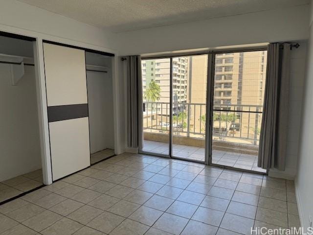 303 Liliuokalani Ave Unit 602, Honolulu, HI 96815 - unfurnished bedroom with access to outside, light tile patterned flooring, a textured ceiling, and multiple closets