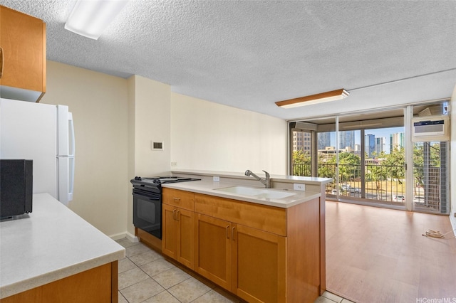 1050 Kinau St Unit 301, Honolulu, HI 96814 - kitchen with a sink, black range, expansive windows, freestanding refrigerator, and a textured ceiling