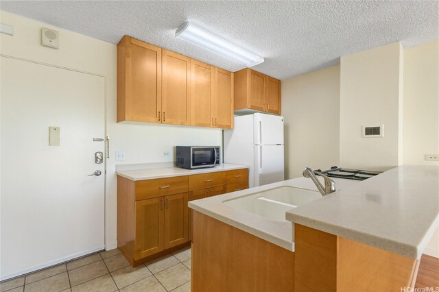 1050 Kinau St Unit 301, Honolulu, HI 96814 - kitchen with stainless steel microwave, freestanding refrigerator, a sink, a peninsula, and light countertops