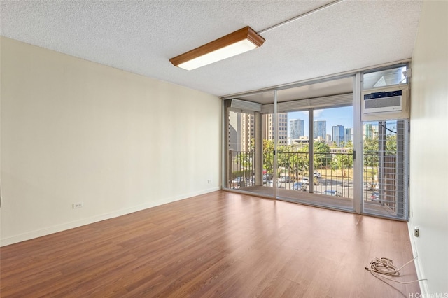 1050 Kinau St Unit 301, Honolulu, HI 96814 - spare room with a wall of windows, a skyline view, wood finished floors, baseboards, and a textured ceiling
