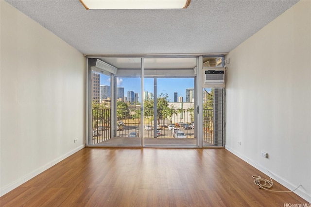 1050 Kinau St Unit 301, Honolulu, HI 96814 - spare room featuring floor to ceiling windows, a view of skyline, wood finished floors, baseboards, and a textured ceiling