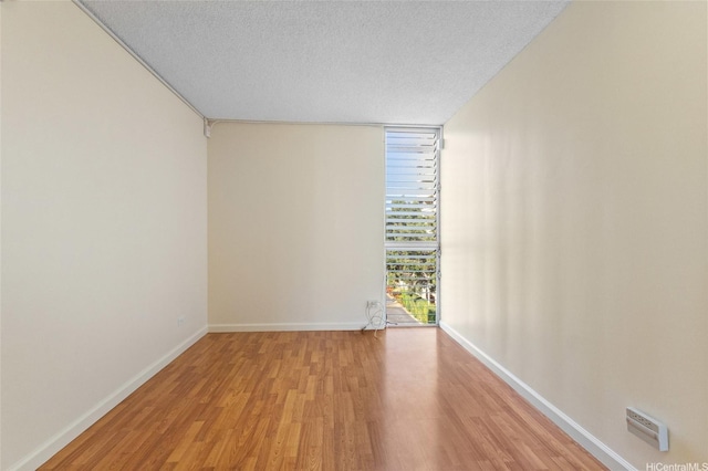 1050 Kinau St Unit 301, Honolulu, HI 96814 - spare room with a wall of windows, a textured ceiling, light wood finished floors, and baseboards