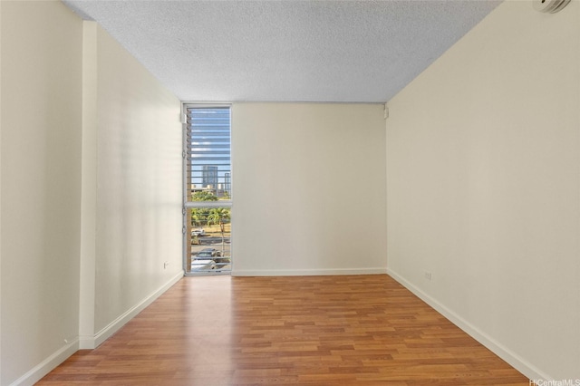 1050 Kinau St Unit 301, Honolulu, HI 96814 - empty room featuring expansive windows, light wood-style flooring, a textured ceiling, and baseboards