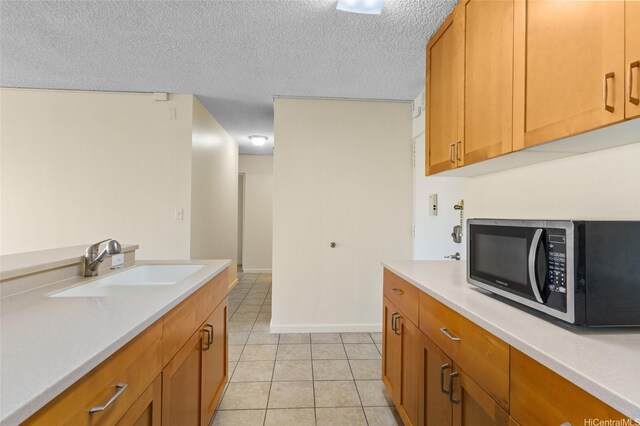 1050 Kinau St Unit 301, Honolulu, HI 96814 - kitchen with a sink, light countertops, a textured ceiling, light tile patterned floors, and brown cabinets