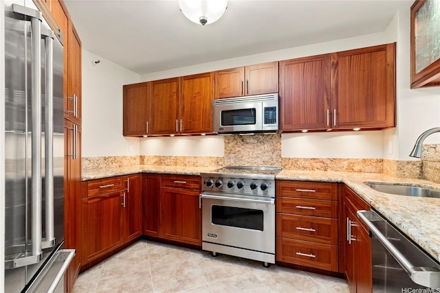 2101 Nuuanu Ave Unit I-1002, Honolulu, HI 96817 - kitchen with high end appliances, a sink, light stone countertops, light tile patterned floors, and brown cabinetry