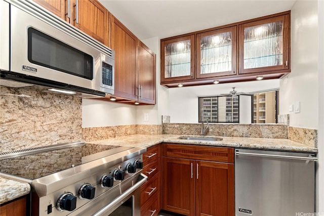 2101 Nuuanu Ave Unit I-1002, Honolulu, HI 96817 - kitchen featuring appliances with stainless steel finishes, glass insert cabinets, a sink, brown cabinets, and decorative backsplash