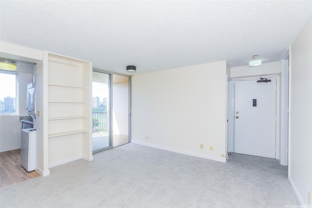 2916 Date St Unit 10I, Honolulu, HI 96816 - unfurnished living room with light carpet, a textured ceiling, plenty of natural light, stacked washer and clothes dryer, and baseboards