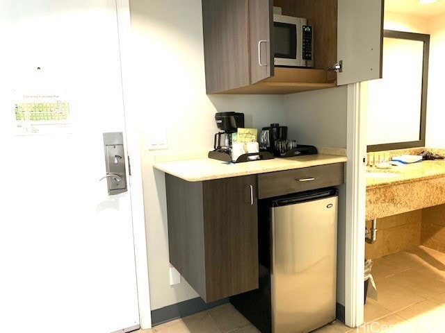 1850 Ala Moana Blvd Unit 819, Honolulu, HI 96815 - kitchen with stainless steel microwave, light countertops, light tile patterned floors, and dark brown cabinetry