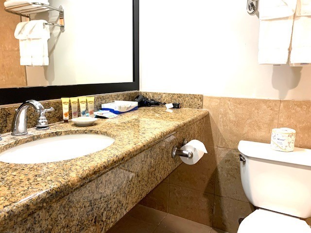 1850 Ala Moana Blvd Unit 819, Honolulu, HI 96815 - bathroom featuring toilet, vanity, tile walls, a wainscoted wall, and tile patterned flooring