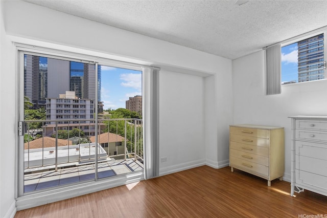 2115 Ala Wai Blvd Unit 501, Honolulu, HI 96815 - bedroom featuring access to outside, wood finished floors, baseboards, a textured ceiling, and multiple windows
