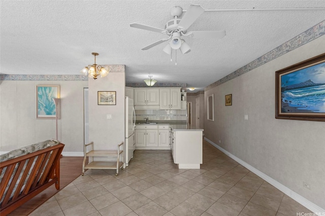 2115 Ala Wai Blvd Unit 501, Honolulu, HI 96815 - kitchen featuring freestanding refrigerator, a textured ceiling, a sink, white cabinetry, and a ceiling fan