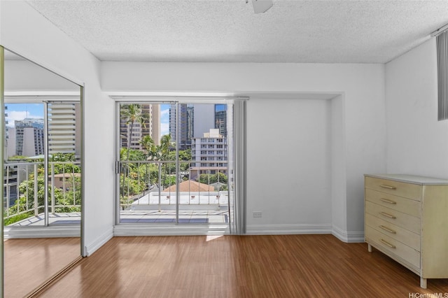 2115 Ala Wai Blvd Unit 501, Honolulu, HI 96815 - empty room with wood finished floors, a view of city, a textured ceiling, and baseboards