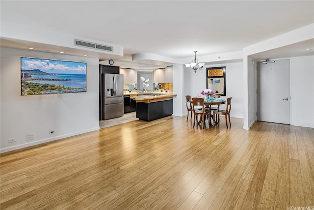 66 Queen St Unit 2904, Honolulu, HI 96813 - kitchen featuring stainless steel fridge, a chandelier, a peninsula, light countertops, and light wood-type flooring