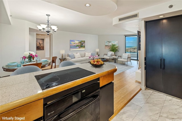 66 Queen St Unit 2904, Honolulu, HI 96813 - kitchen with wall oven, black electric stovetop, a chandelier, light marble finish flooring, and open floor plan