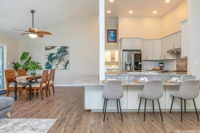94-457 Akoa Pl, Mililani, HI 96789 - kitchen featuring stainless steel fridge with ice dispenser, a sink, light stone counters, a peninsula, and light wood-style floors