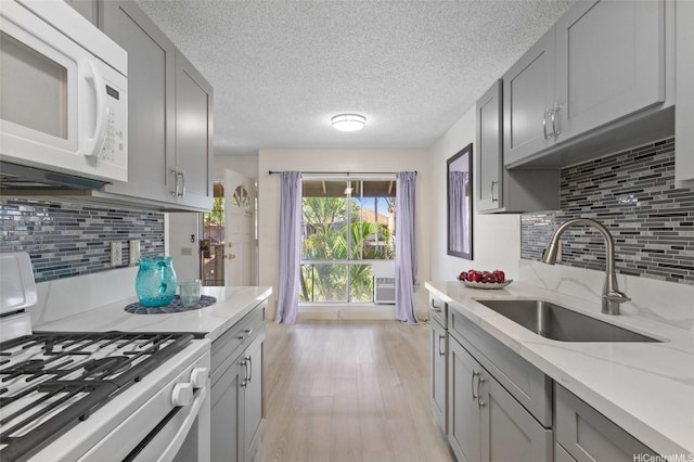 91-1040 Puamaeole St Unit 13R, Ewa Beach, HI 96706 - kitchen featuring white appliances, a sink, gray cabinets, light wood-type flooring, and decorative backsplash