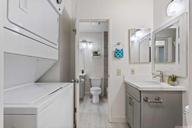 91-1040 Puamaeole St Unit 13R, Ewa Beach, HI 96706 - bathroom with estacked washer and dryer, toilet, vanity, baseboards, and wood finished floors