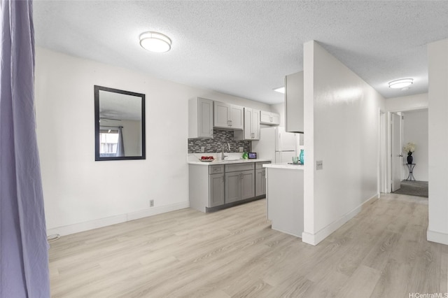 91-1040 Puamaeole St Unit 13R, Ewa Beach, HI 96706 - kitchen with gray cabinetry, freestanding refrigerator, light wood finished floors, a sink, and light countertops