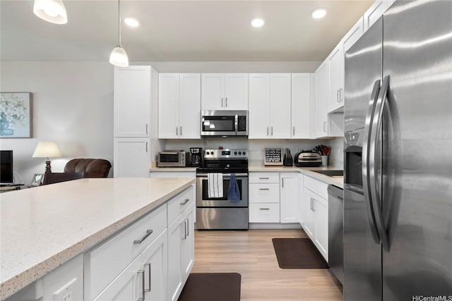 91-3524 Iwikuamoo St Unit 402, Ewa Beach, HI 96706 - kitchen featuring appliances with stainless steel finishes, white cabinetry, light wood-style flooring, light stone countertops, and recessed lighting
