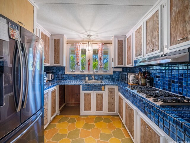 509 Lawelawe St, Honolulu, HI 96821 - kitchen featuring appliances with stainless steel finishes, under cabinet range hood, a sink, backsplash, and dark countertops