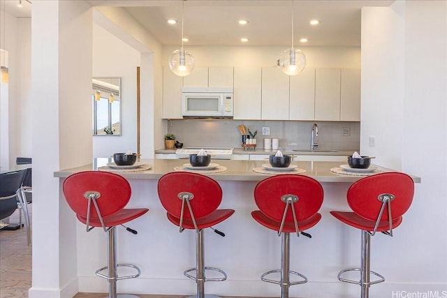 229 Paoakalani Ave Unit Ph-3807, Honolulu, HI 96815 - kitchen featuring white microwave, a breakfast bar, stove, recessed lighting, and light countertops