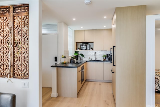 2943 Kalakaua Ave Unit 606, Honolulu, HI 96815 - kitchen with light wood finished floors, dark countertops, decorative backsplash, stainless steel oven, and modern cabinets