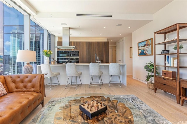 1118 Ala Moana Blvd Unit 2505, Honolulu, HI 96814 - kitchen with light wood finished floors, island exhaust hood, a breakfast bar area, and modern cabinets
