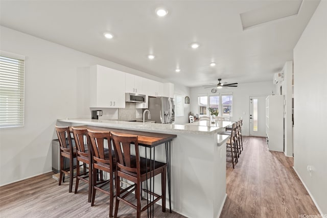 91-1774 Kohanahana Loop, Ewa Beach, HI 96706 - kitchen featuring appliances with stainless steel finishes, a kitchen breakfast bar, light wood-style floors, a peninsula, and recessed lighting
