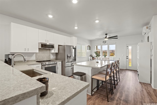 91-1774 Kohanahana Loop, Ewa Beach, HI 96706 - kitchen with stainless steel appliances, a kitchen island, ceiling fan, a breakfast bar area, and a wall mounted AC