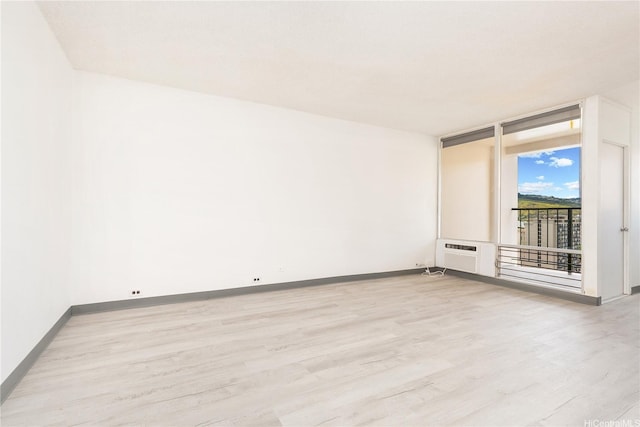 747 Amana St Unit 1607, Honolulu, HI 96814 - empty room featuring light wood-style floors, a wall mounted air conditioner, and a wall of windows