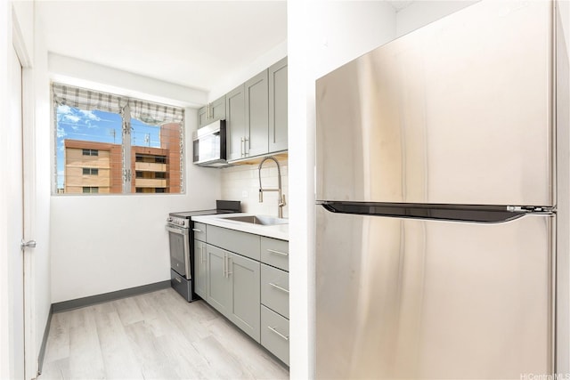 747 Amana St Unit 1607, Honolulu, HI 96814 - kitchen with stainless steel appliances, gray cabinetry, light wood-type flooring, tasteful backsplash, and light countertops
