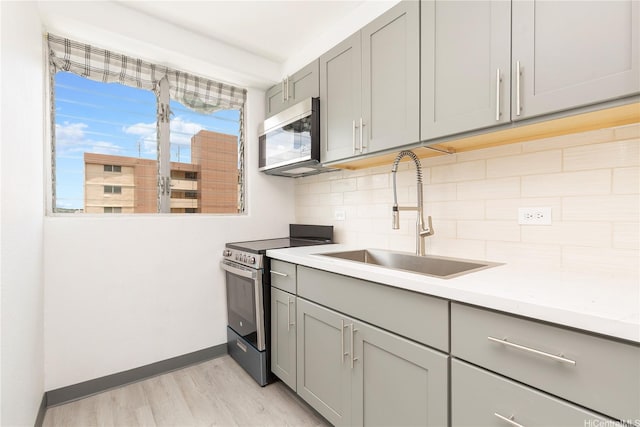 747 Amana St Unit 1607, Honolulu, HI 96814 - kitchen featuring gray cabinetry, appliances with stainless steel finishes, light wood finished floors, decorative backsplash, and light countertops
