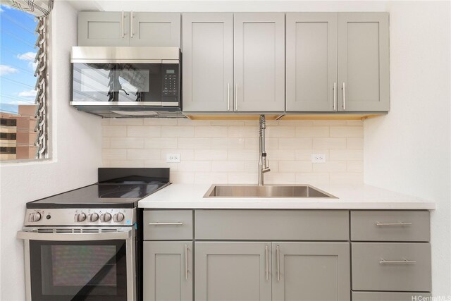 747 Amana St Unit 1607, Honolulu, HI 96814 - kitchen featuring appliances with stainless steel finishes, gray cabinetry, decorative backsplash, and light countertops